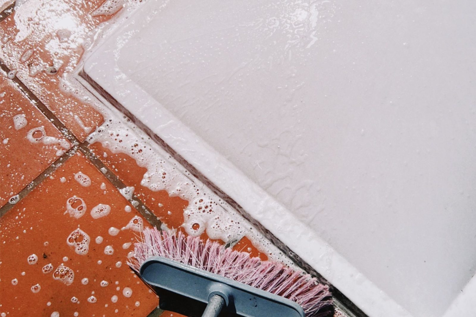 Scrub brush and soap cleaning tile grout during a deep clean