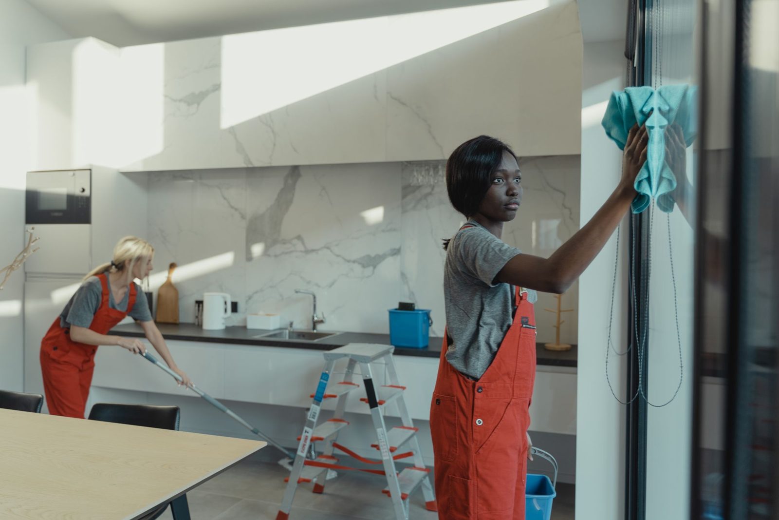 Two cleaners wiping down a kitchen together